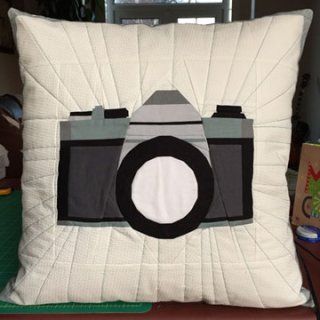 a camera pillow sitting on top of a chair