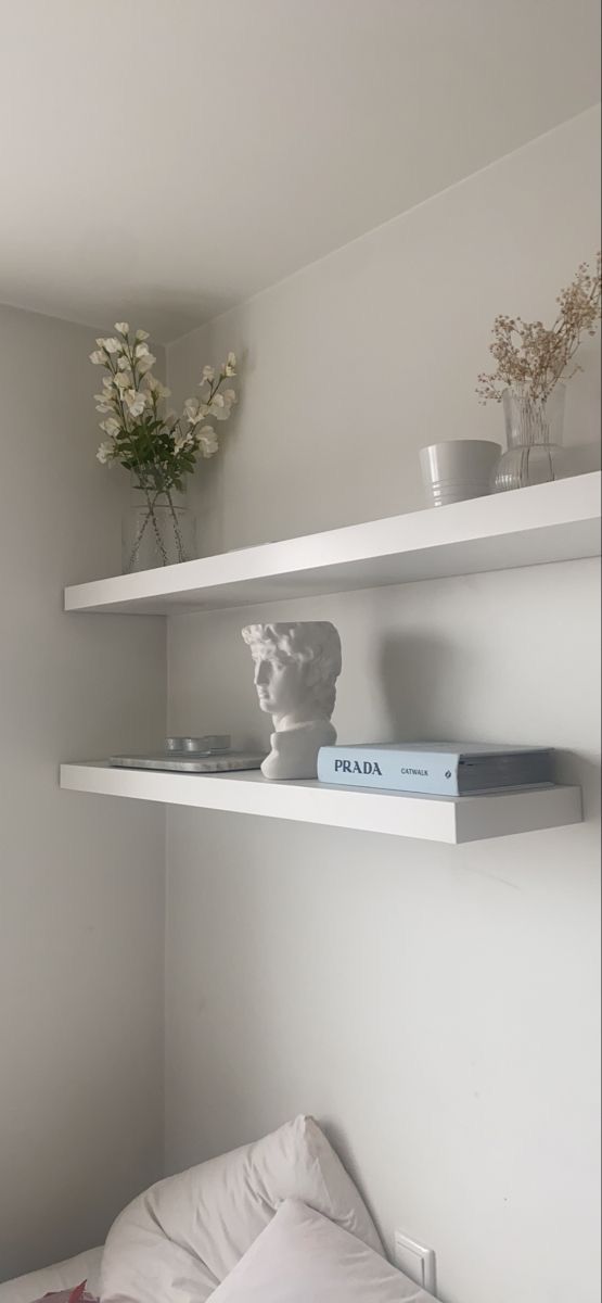 two white shelves with books and vases on them