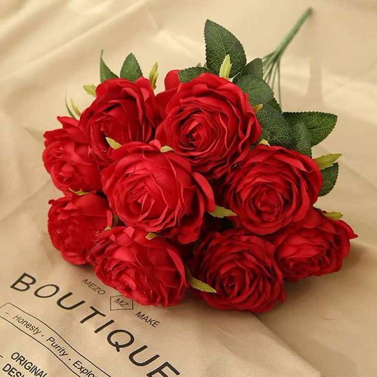 a bouquet of red roses sitting on top of a piece of paper