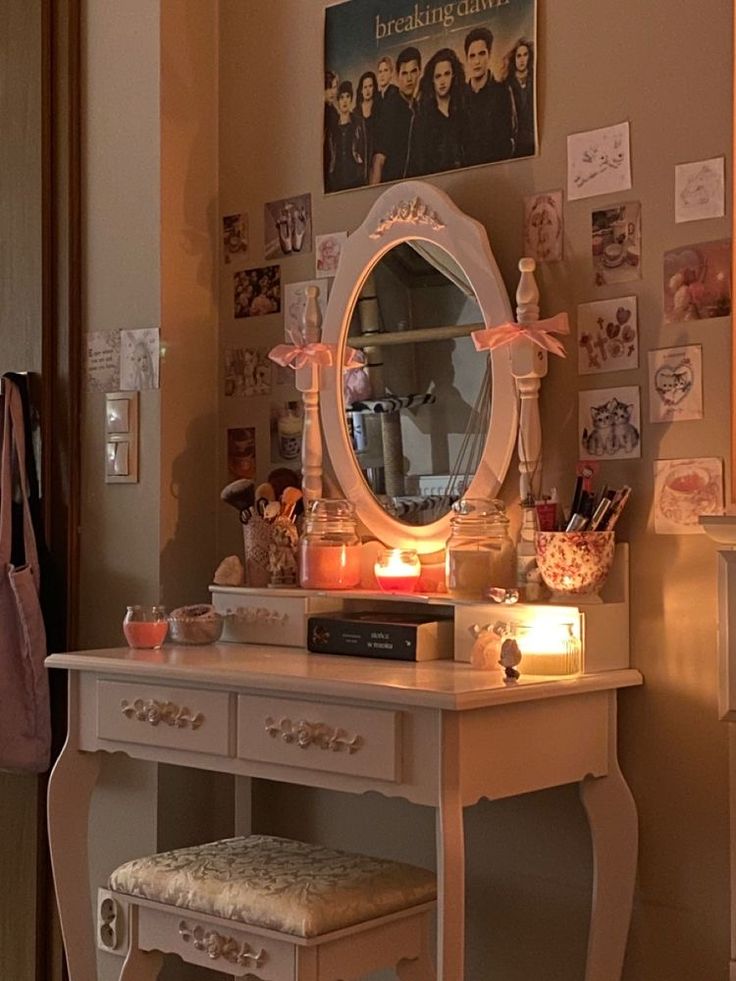 a vanity with a mirror, stool and pictures on the wall above it in a bedroom