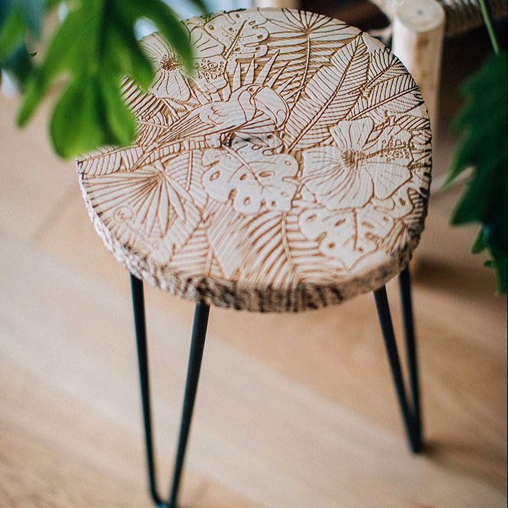 a wooden stool sitting on top of a hard wood floor next to a potted plant