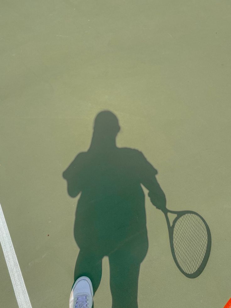 the shadow of a person holding a tennis racket