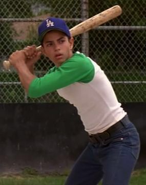 a young man holding a baseball bat on top of a field