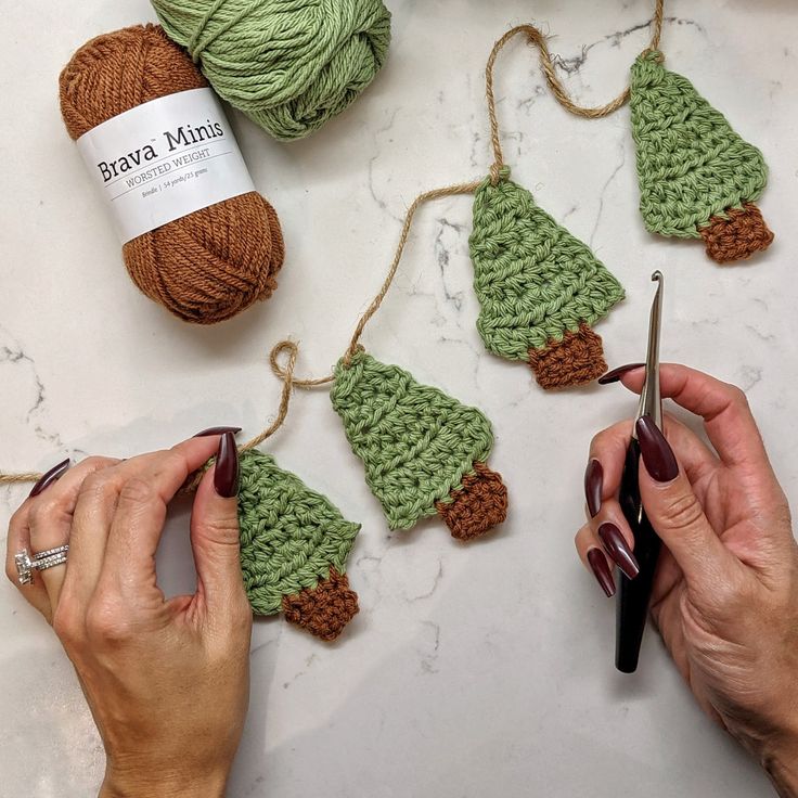 crocheted christmas tree ornaments being worked on by two hands with yarn in the background