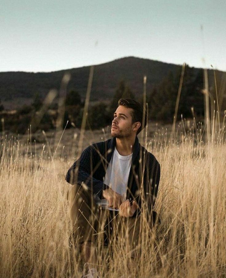 a man is sitting in the tall grass