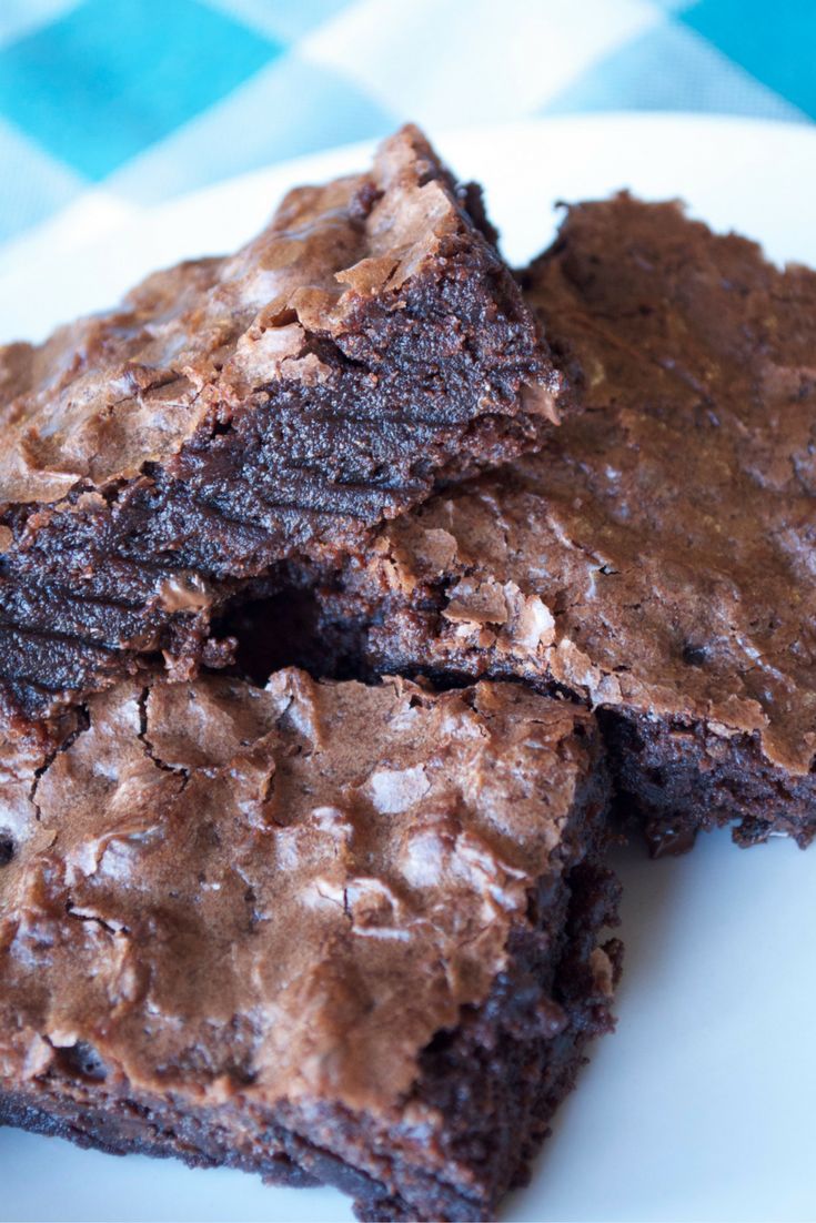 three chocolate brownies stacked on top of each other in front of a blue and white checkered tablecloth