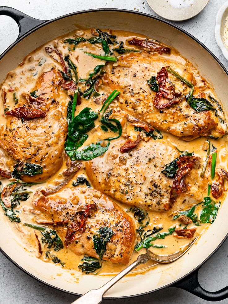 a pan filled with chicken and spinach covered in gravy on top of a table