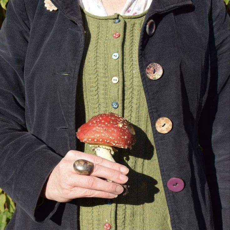 a woman holding a mushroom in her hand with buttons all over the outer part of it