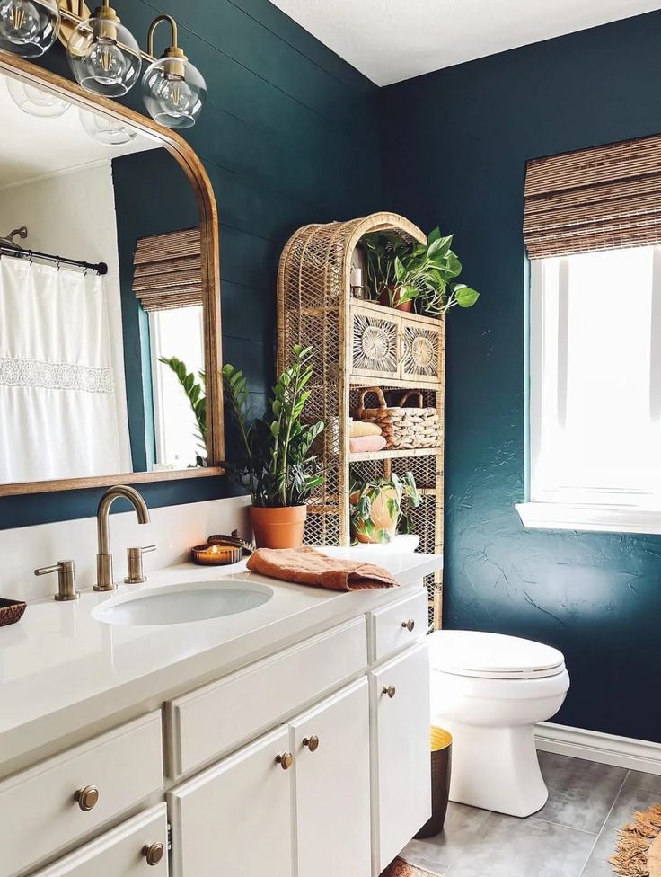 a bathroom with blue walls, white cabinets and a large mirror over the toilet area