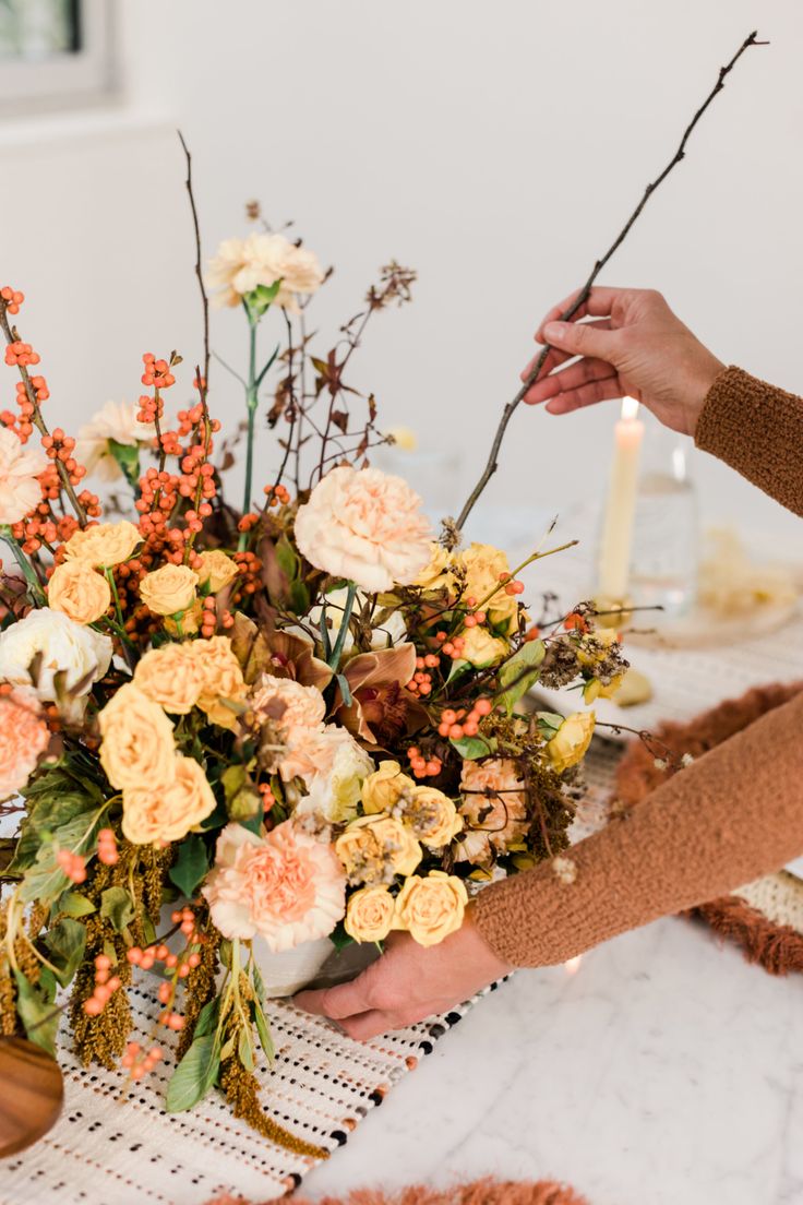 a woman is arranging flowers on a table