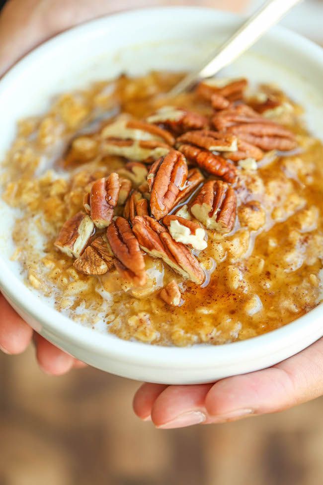 someone holding a bowl of oatmeal with pecans in it