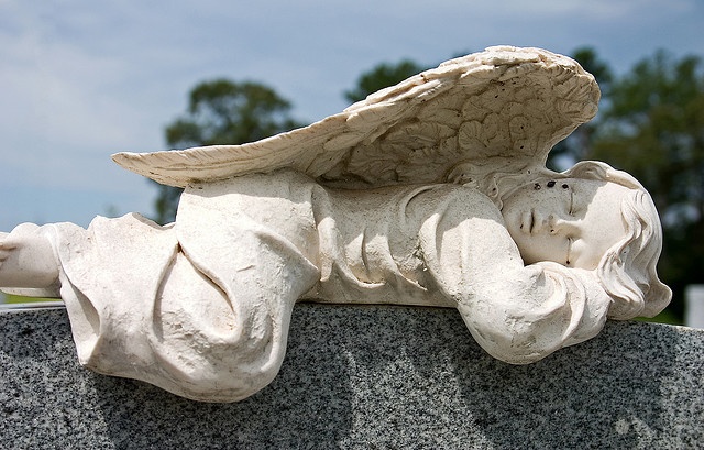 an angel statue laying on top of a stone slab