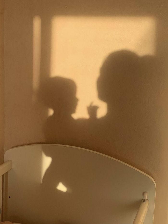 the shadow of two people on a wall next to a bed