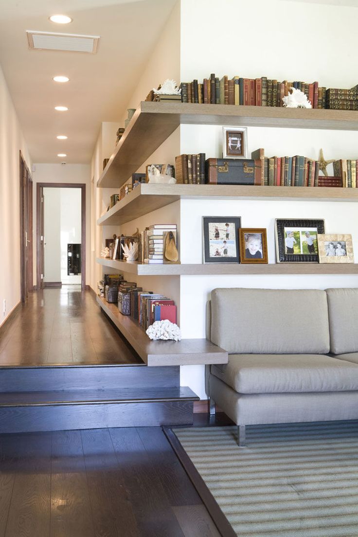 a living room filled with furniture and bookshelves next to a doorway that leads to a hallway