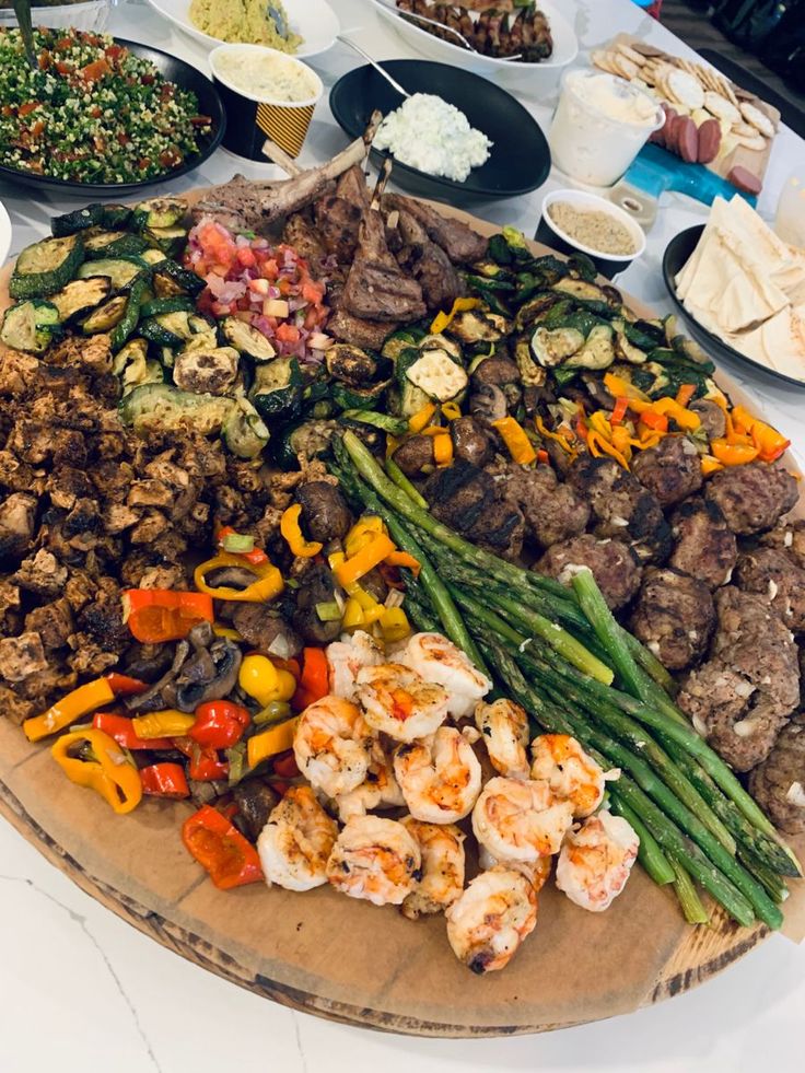 an assortment of food is displayed on a wooden platter with utensils and plates