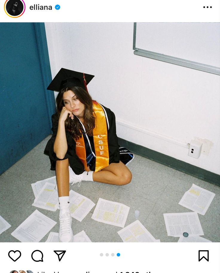 a young woman sitting on the floor in her graduation cap and gown