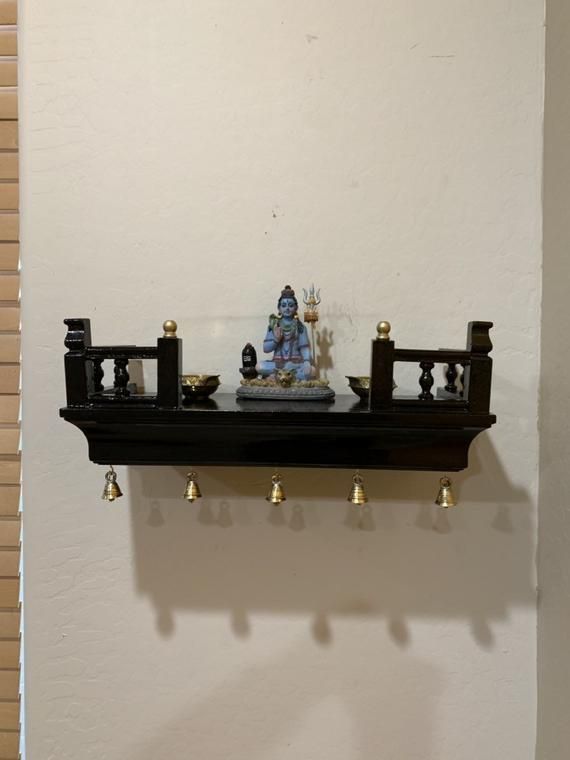 there is a shelf with statues on it and bells hanging from the wall behind it