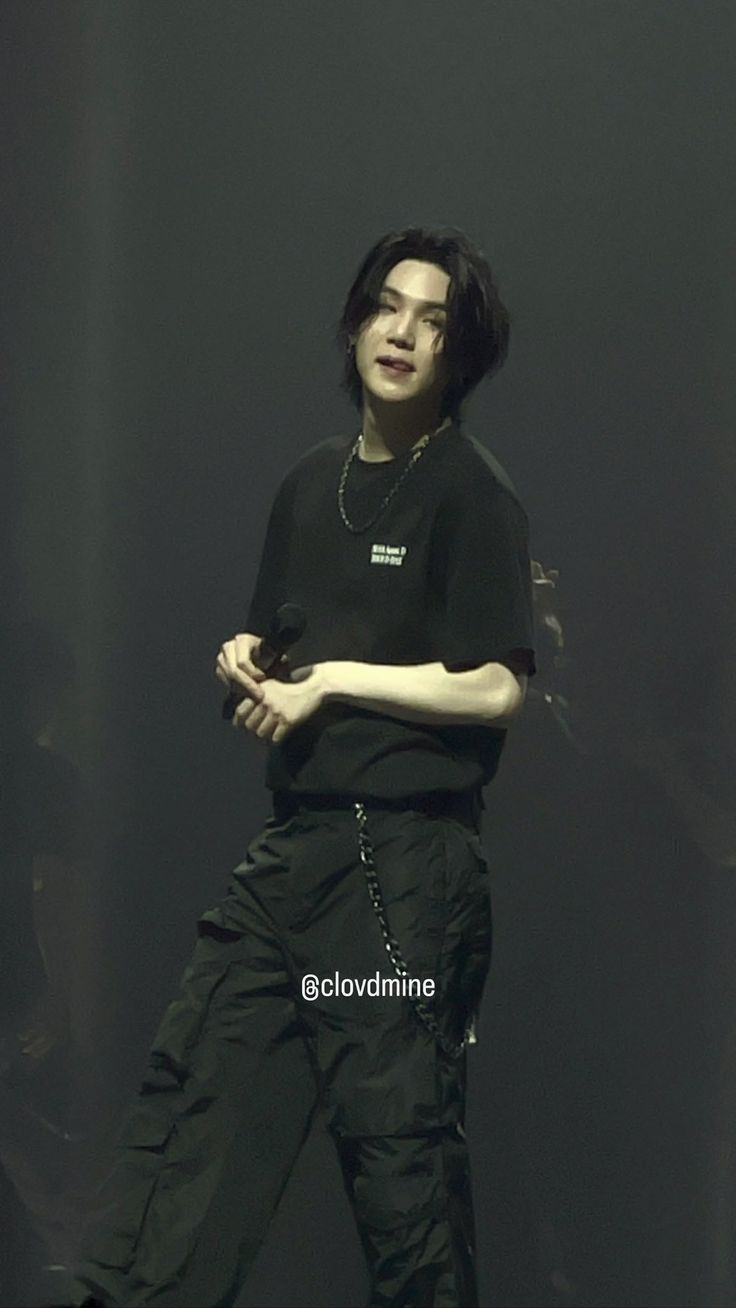 young man in black shirt and pants standing on stage