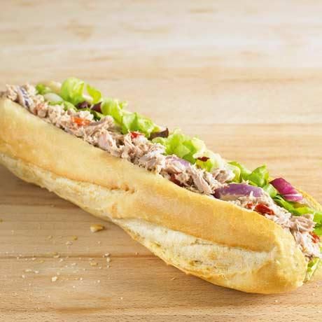 a sandwich with meat, lettuce and red onions on a wooden table top