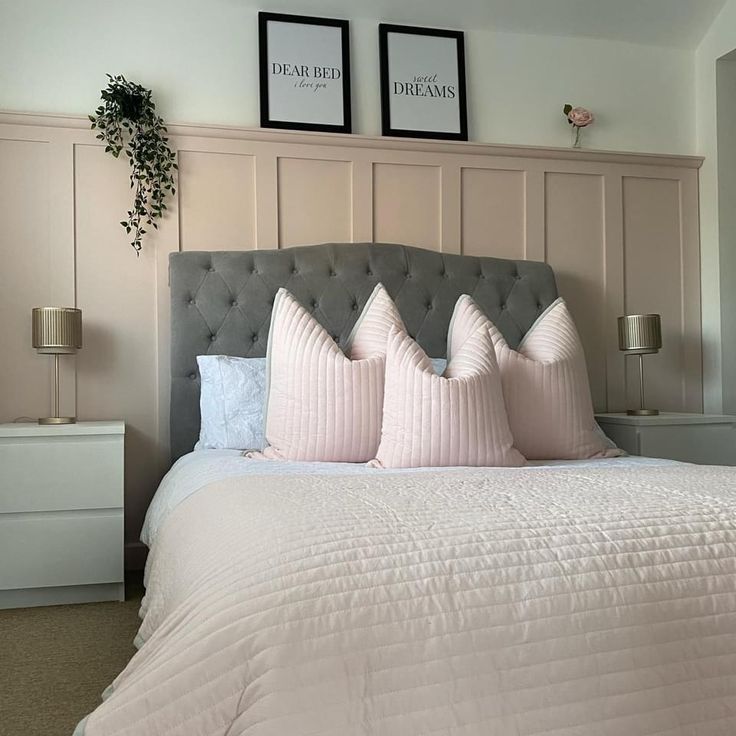 a bed with pink pillows and two framed pictures above the headboard in a bedroom