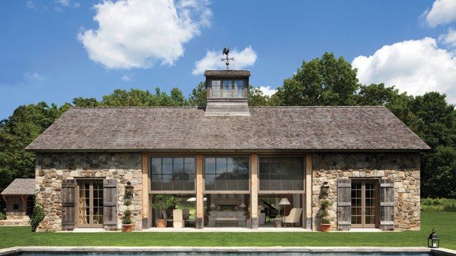 the pool house is next to an outdoor swimming pool and has large windows that look out onto the trees