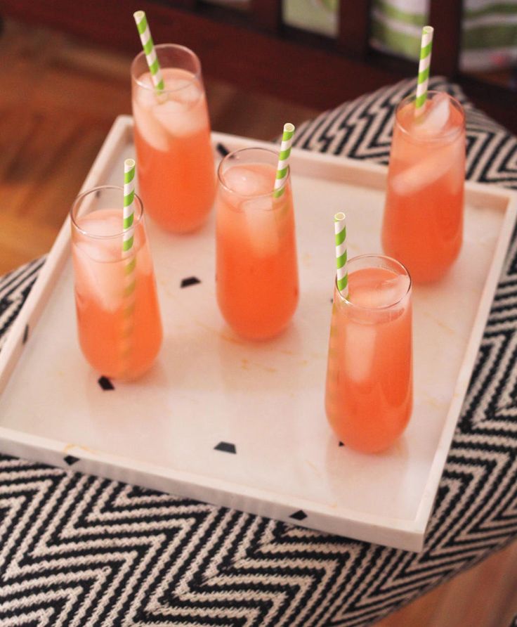 four glasses filled with drinks sitting on top of a tray