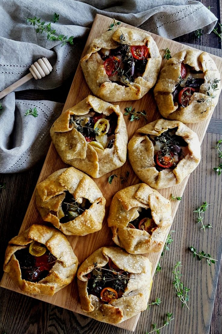 a wooden cutting board topped with mini pies