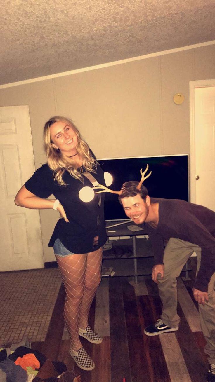 a man and woman standing in front of a fireplace with reindeer antlers on their heads