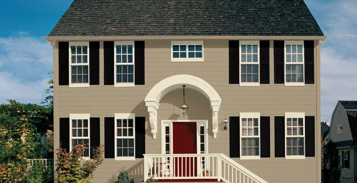 a large house with black shutters and red door