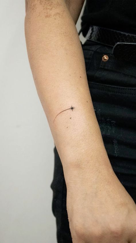 a person with a small cross tattoo on their arm