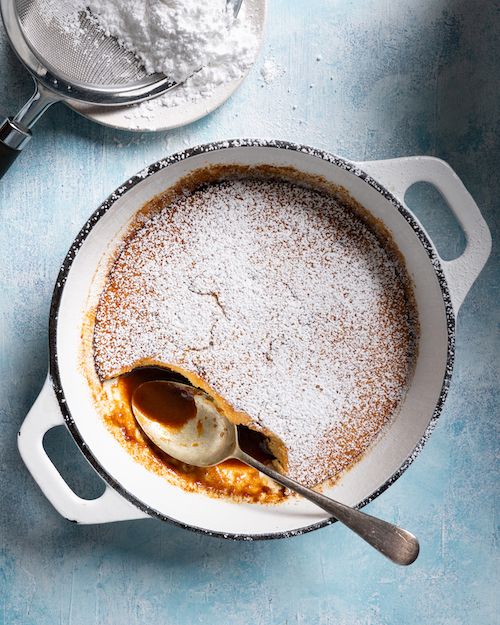 a pot filled with powdered sugar next to a bowl full of other ingredients on a blue surface