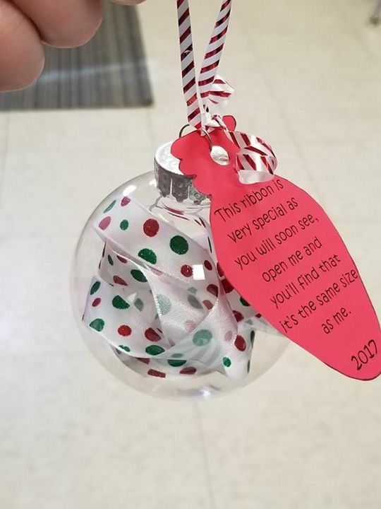 a hand holding a glass ornament with a tag on it