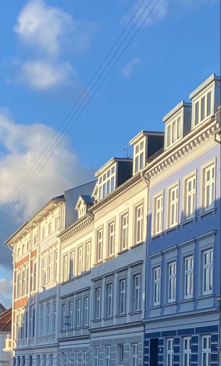 a row of white and blue buildings with clouds in the background