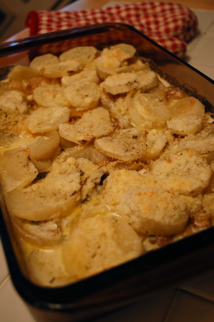 a casserole dish with potatoes in it on a counter top next to a red and white checkered napkin