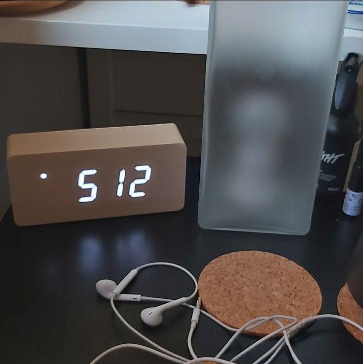 an alarm clock sitting on top of a table next to headphones