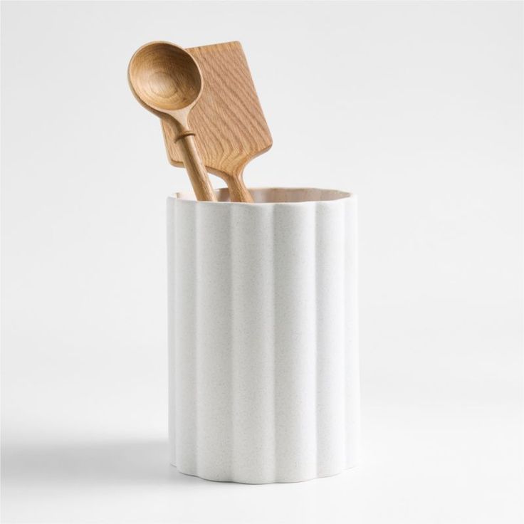 two wooden spoons in a white cup