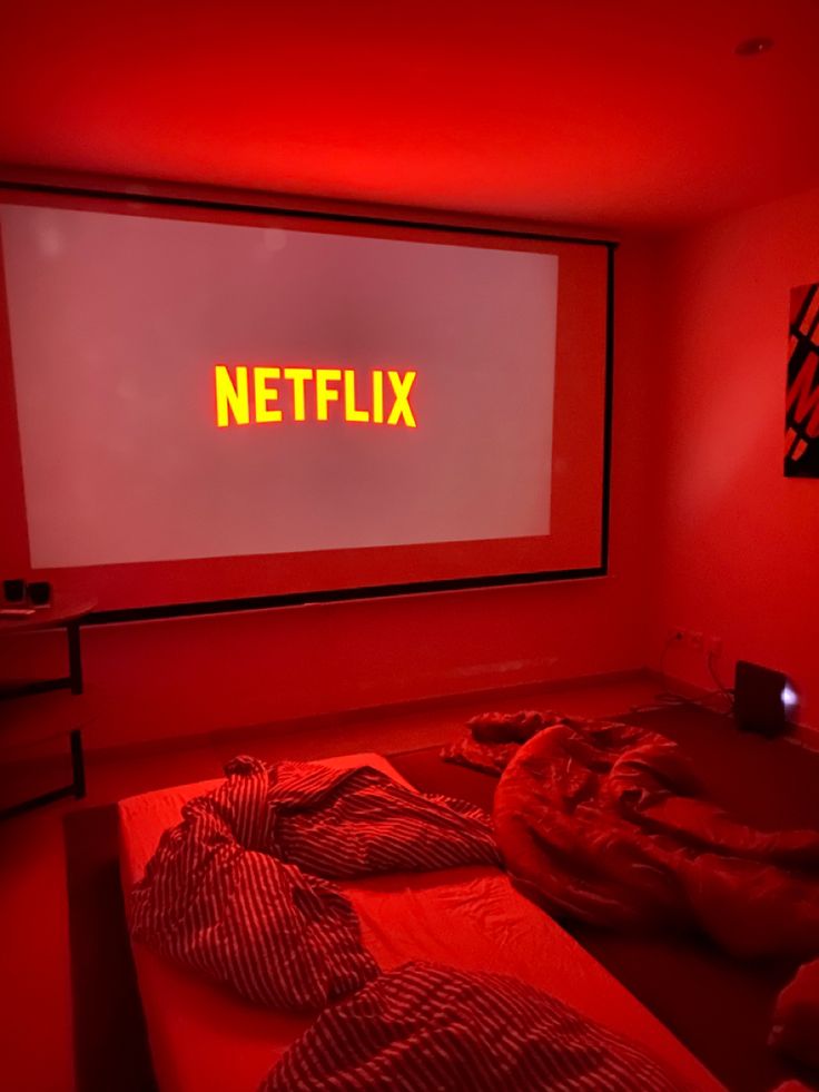 a red room with two beds in front of a projector screen and the word netflix on it