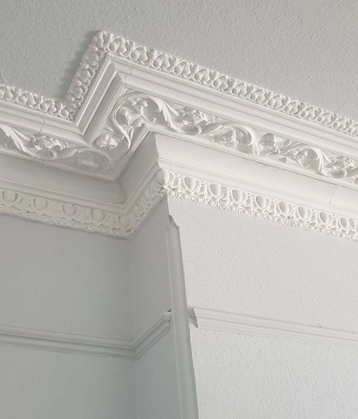 an ornate white crown molding on the ceiling