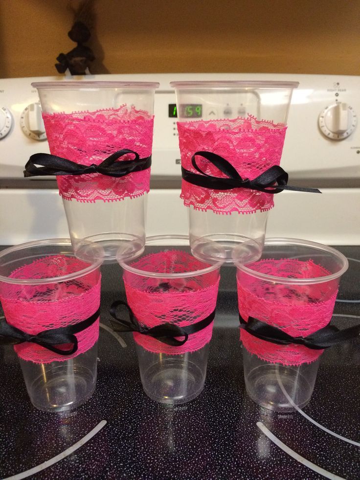 four cups with pink lace and black bows are sitting on top of the stove in front of an oven