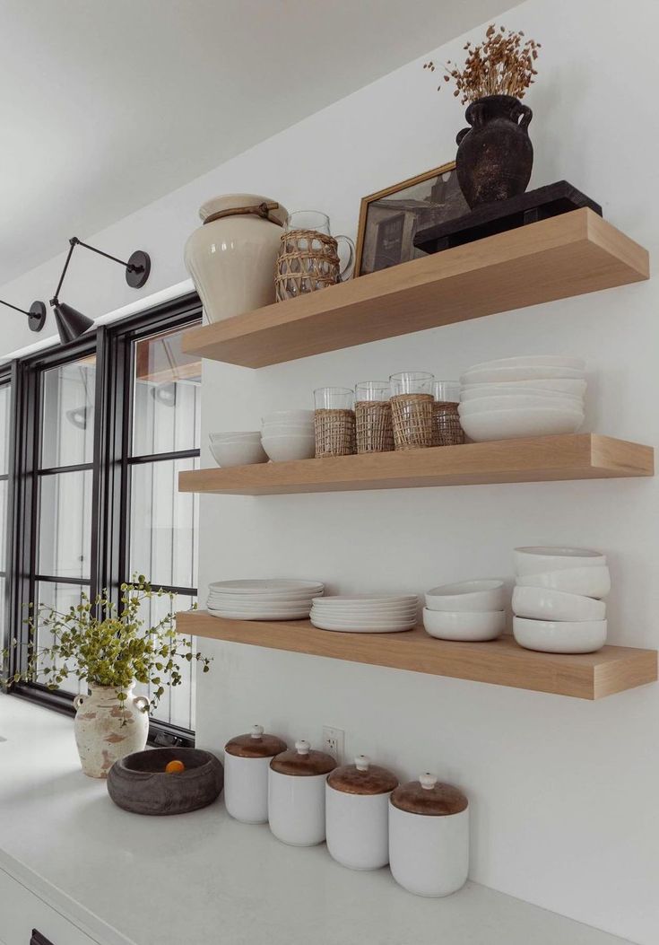 the shelves in the kitchen are filled with plates, bowls and vases on them