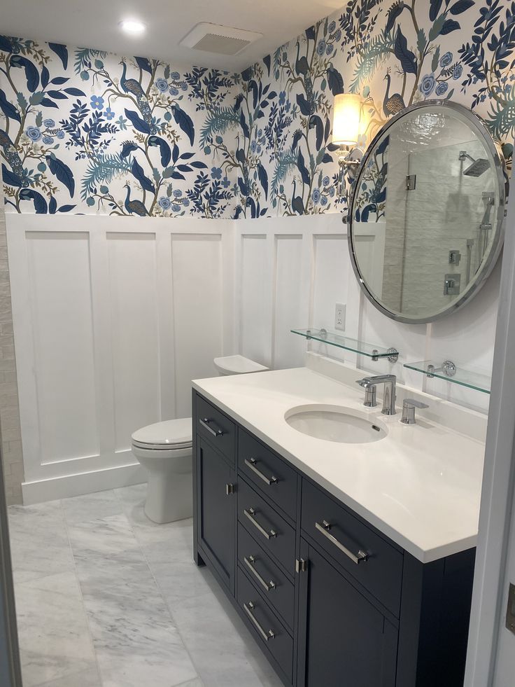 a bathroom with blue and white wallpaper on the walls, toilet and sink area