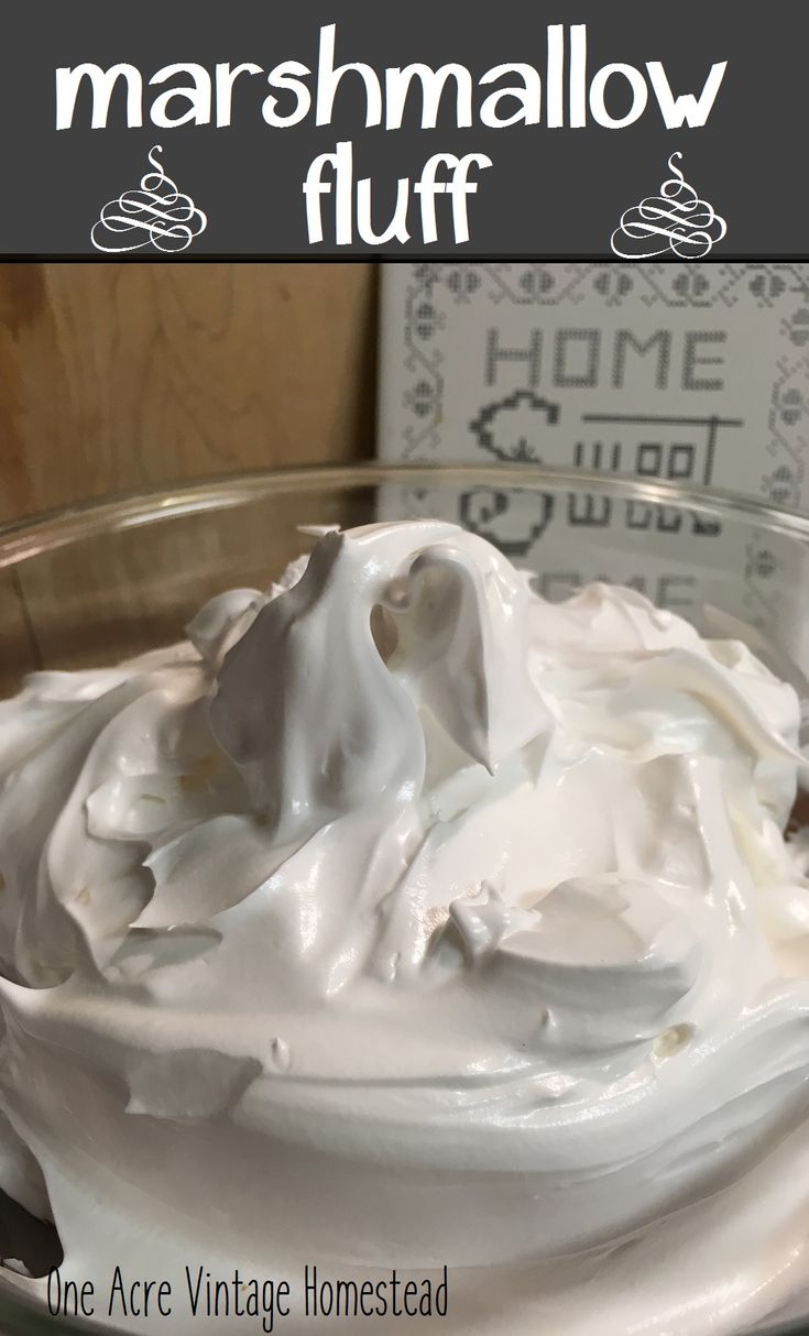 a glass bowl filled with whipped cream on top of a wooden table next to a sign that reads marshmallow fluff