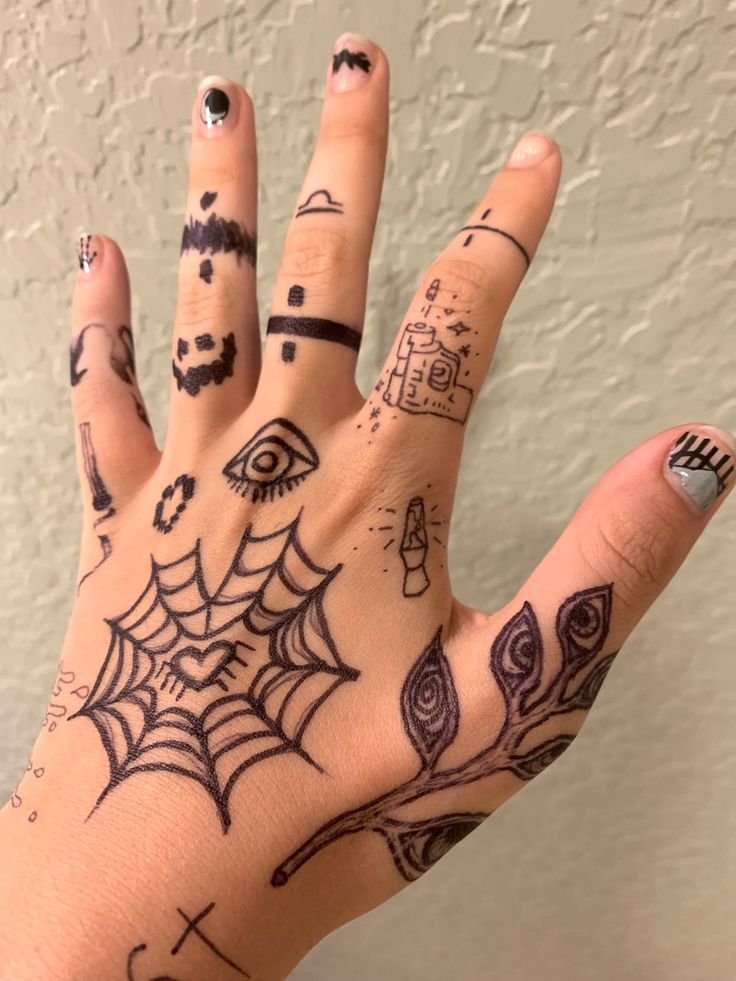 A hand with various doodles on it; including a heart-shaped spider web, a plant with eyes on the leaves, simple lava lamp and gun designs, and bands of different patterns on the fingers. Sharpie Hand Doodles, Sharpie Doodles, Grunge Tattoo, Pretty Hand Tattoos, Finger Tattoo Designs, Sharpie Tattoos, Pen Tattoo, Hand Doodles, Hand Drawings