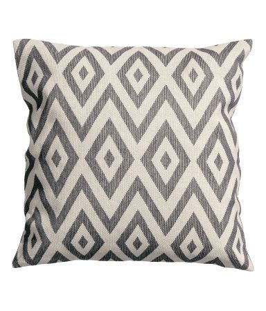 a gray and white pillow with diamond shapes on it's side, against a white background