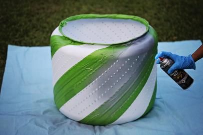 a person spray painting an inflatable object with green and white stripes on it