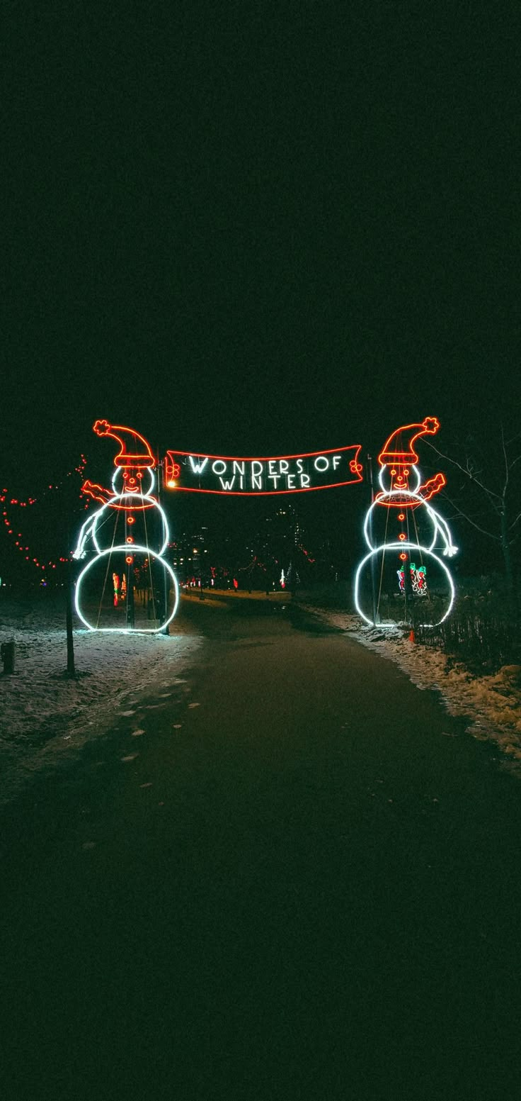 two snowmen are lit up at night with lights on them and the words winter written in large letters