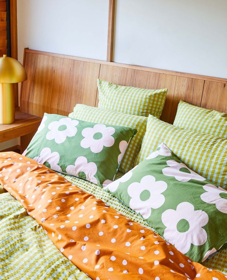 a bed with green and white flowers on the covers, pillows and pillowcases