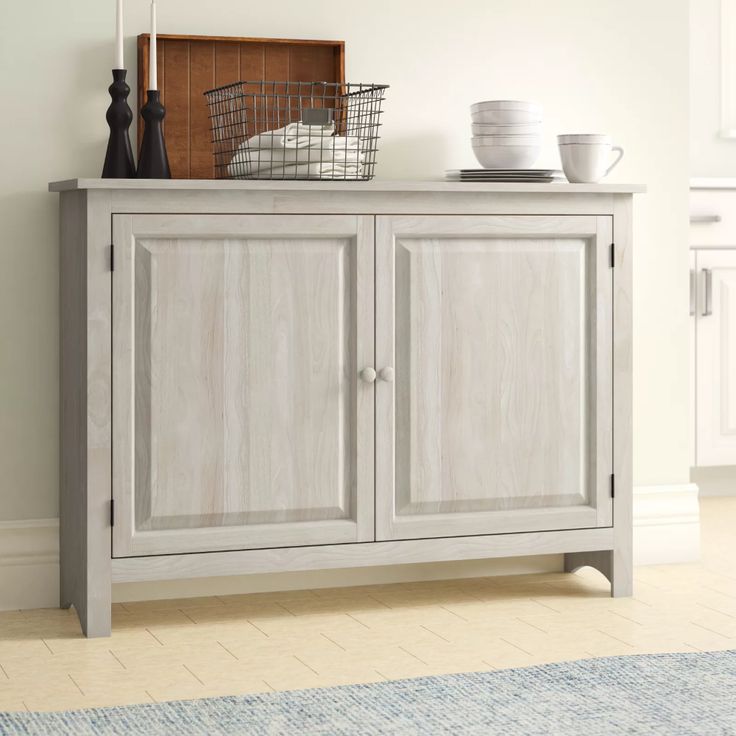 a white cabinet sitting on top of a wooden floor next to a rug and window