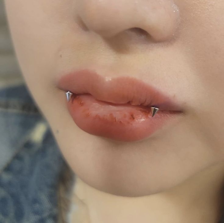 a close up of a woman's lip with piercings on it and her nose