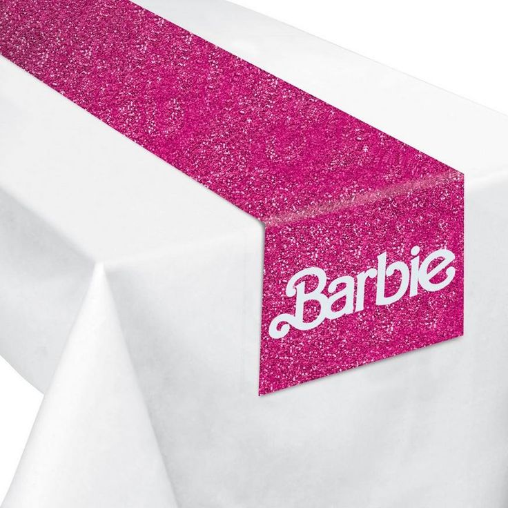 a table topped with a white and pink table cloth next to a sign that says barbie